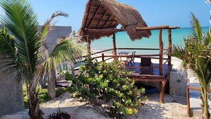 A beachside structure with a thatched roof, wooden seating, and a view of the ocean. - Cascada suite. Private Waterfall Pool & Cinema Screen I Beachfront Sanctuary (Chuburná)