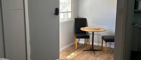 A bedroom with a bed, a small round table with a chair, and a window.