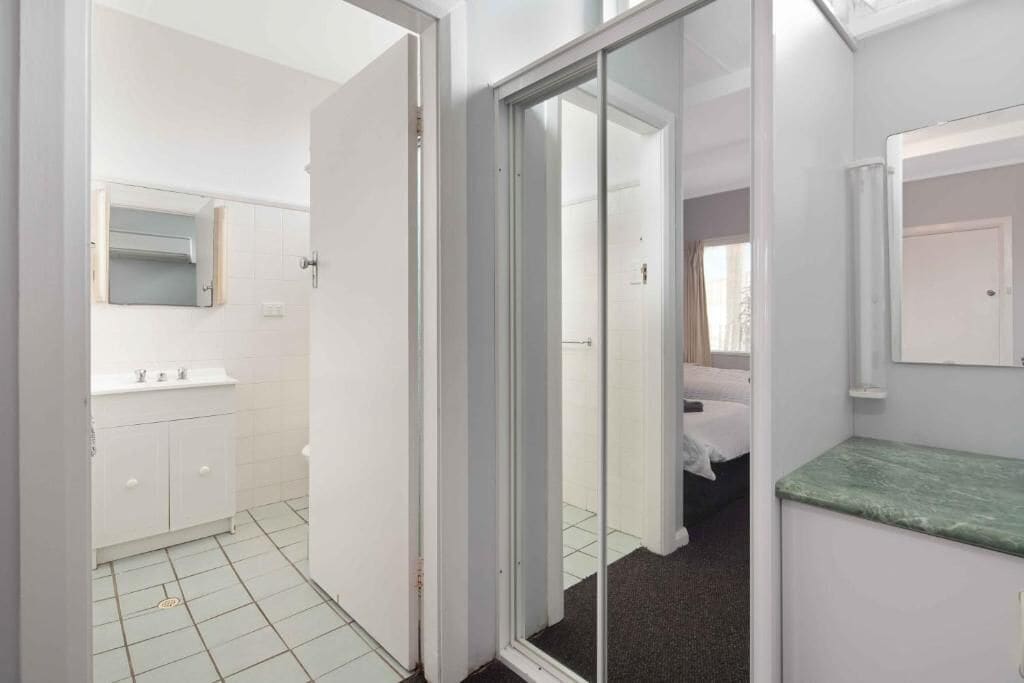 Habitación de hotel con baño, una cama y una encimera verde.