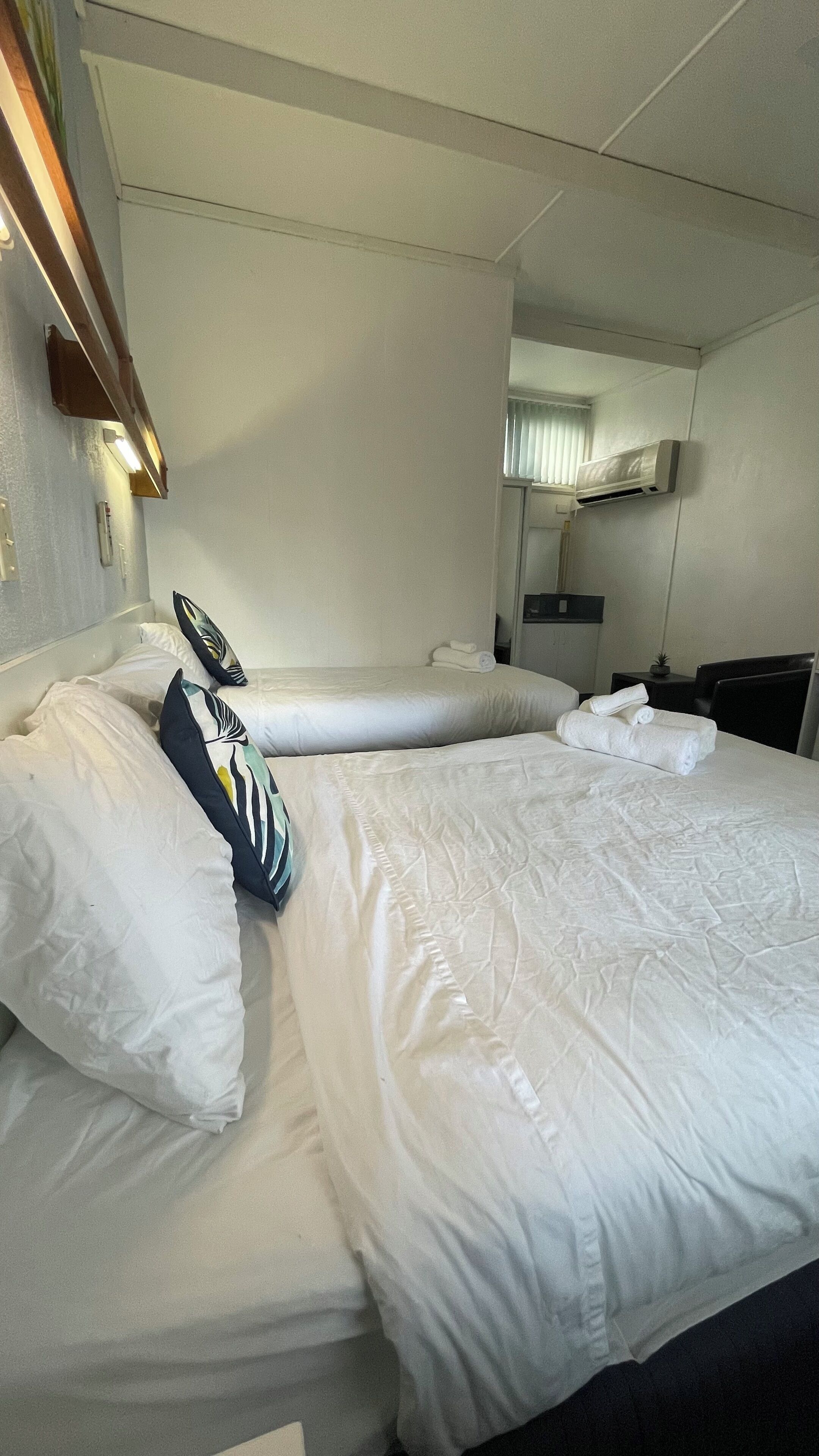 Une chambre d’hôtel équipée d’un lit, d’oreillers, d’une table de chevet, d’un miroir et d’un appareil de climatisation.