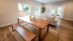 Un salón amplio con una mesa de comedor de madera, un conjunto de sofás y un ventanal que proporciona luz natural.