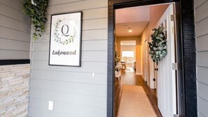 Un pasillo con un cartel enmarcado que dice "Lakewood", una pared de piedra y una puerta que da a una habitación.