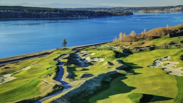 Campo de golf con un río y un área boscosa al fondo.