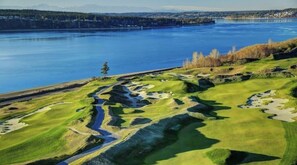 Campo de golf con un río y un área boscosa al fondo.