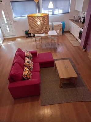 A modern living room with a red sectional sofa, a wooden coffee table, and a dining area with a white table and chairs.