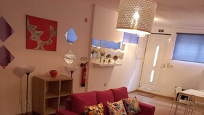 A modern living room with a red sofa, a wooden coffee table, and a hanging light fixture.