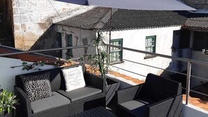 An outdoor seating area with wicker furniture and a large umbrella providing shade.