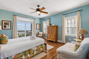 A bedroom with a bed, a chair, a cabinet, and a ceiling fan.