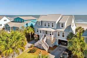 A coastal house with a large deck, a garage, and a view of the ocean.
