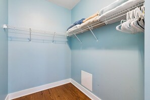 Ein Zimmer mit einem weißen Drahtregal, Holzboden und einer hellblauen Wand.