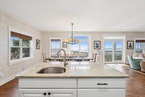 A spacious kitchen with a large island, white cabinetry, and a view to the outside.