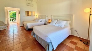 A bedroom with two beds, a ceiling fan, a window, and a door leading to a balcony. - HOTEL TODOBLANCO (Las Galeras)