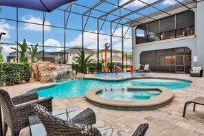 A pool area with a hot tub, outdoor seating, and a waterfall feature.