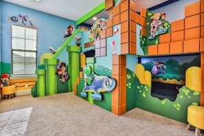 A children's playroom with colorful wall decorations, a window, and a carpeted floor.