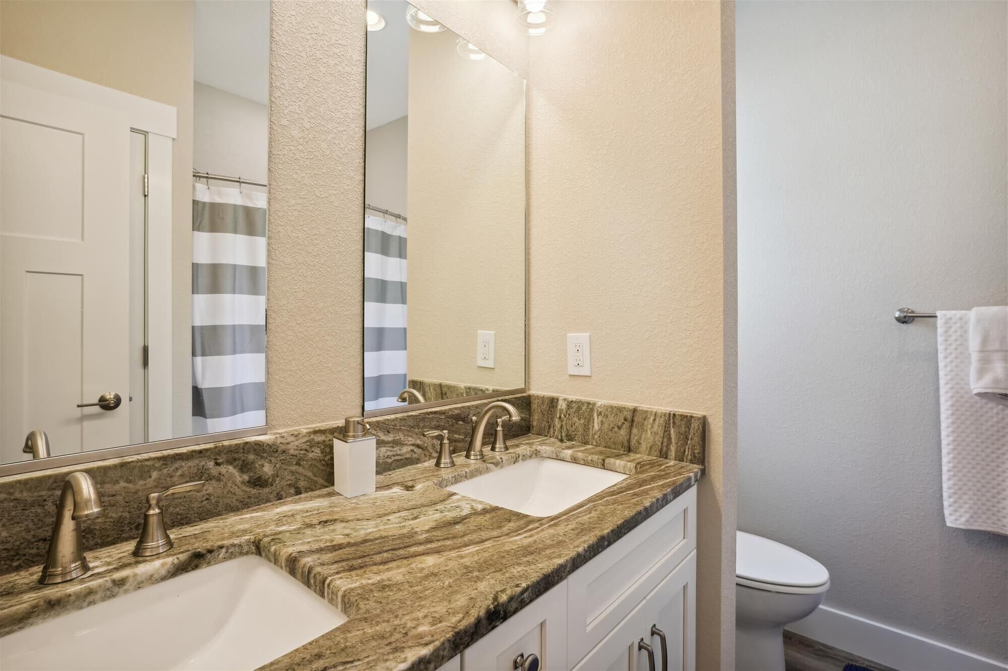 A bathroom with two sinks, a large mirror, and a toilet.