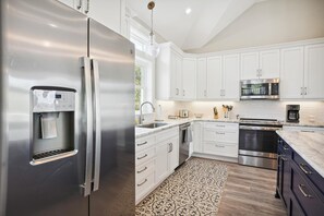 Enjoy cooking in this well-lit kitchen with a refrigerator, microwave, and oven.
