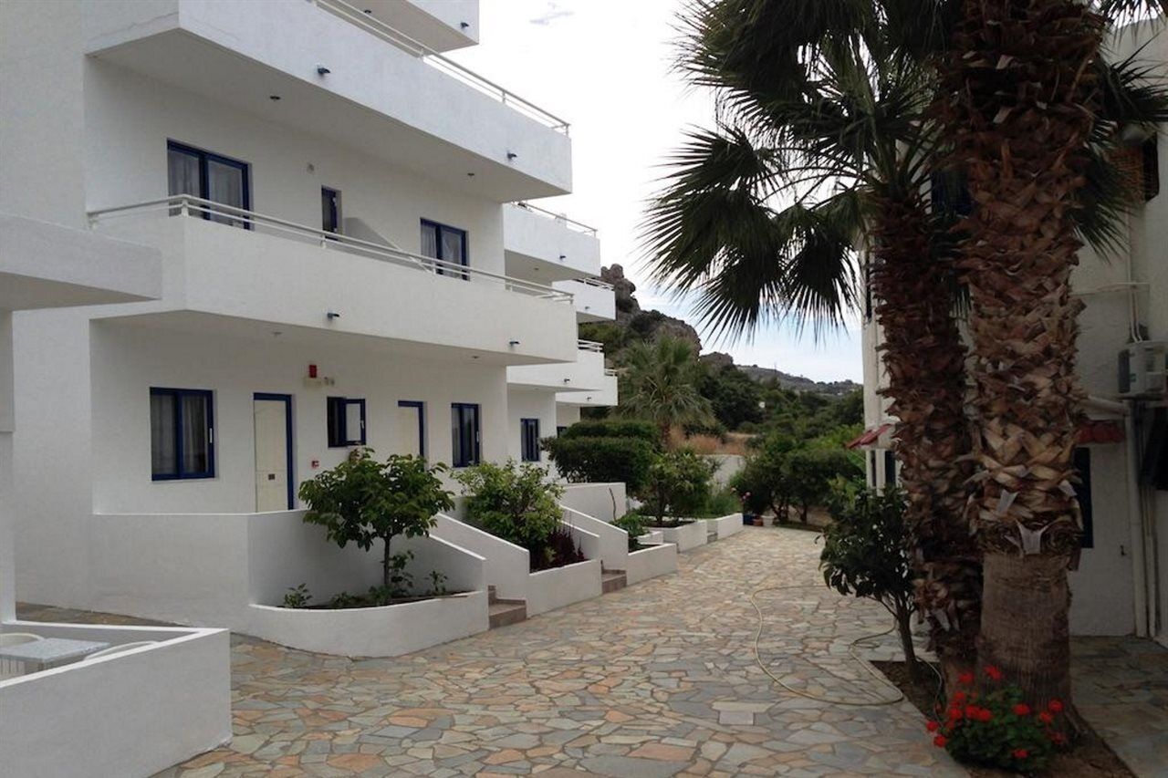 A white building with multiple balconies and a stone-paved courtyard.
