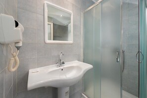 A bathroom with a white sink, a mirror, and a glass shower enclosure. - Palm Bay (Rhodes)