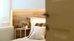 Un dormitorio con cabecera de madera, una mesita de noche con un florero y un radiador blanco.