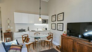 Un espacio habitable compacto con kitchenette, comedor y televisor de pantalla plana.