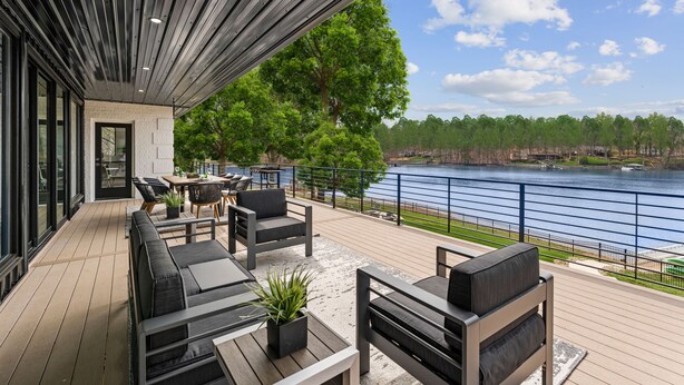 Eine überdachte Terrasse mit Sitzgelegenheit und Blick auf einen See.