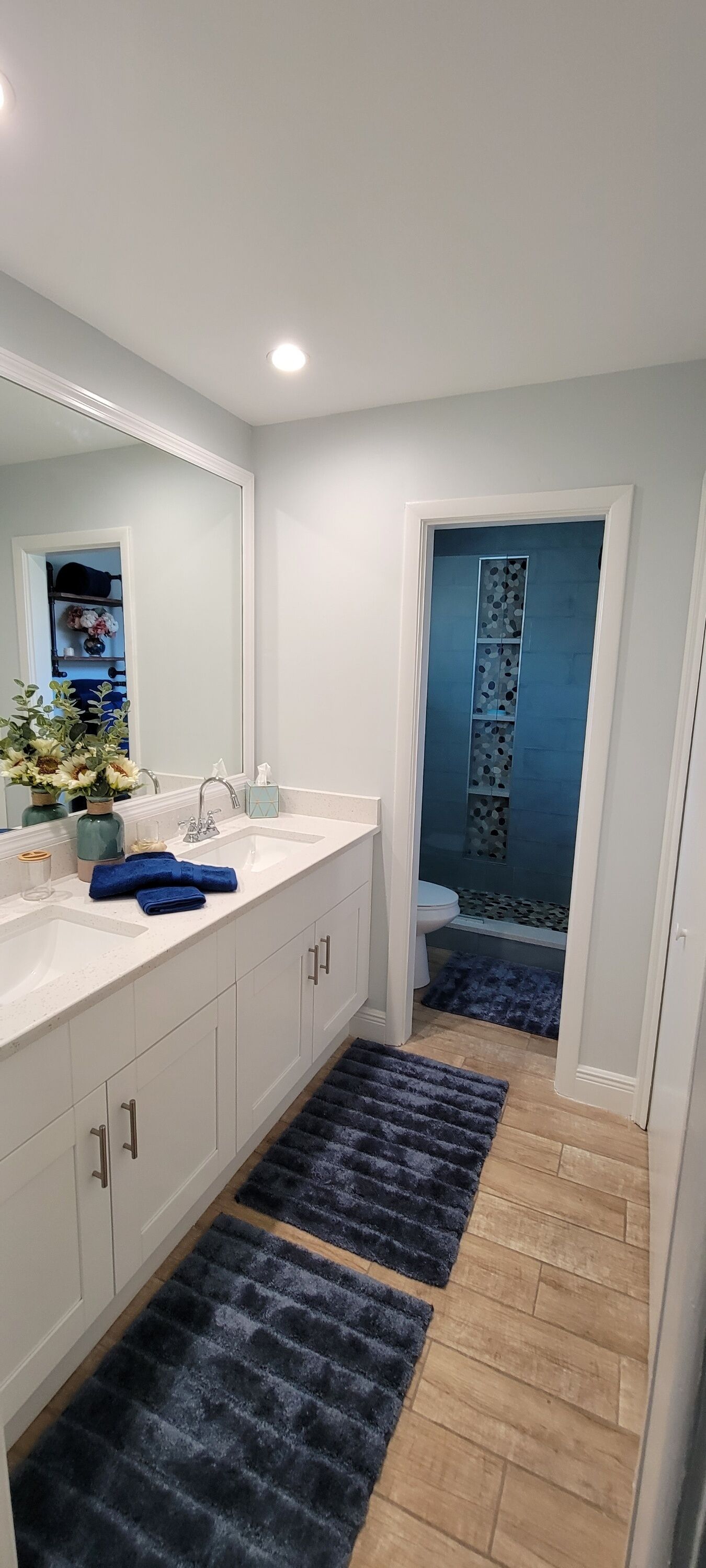 A modern bathroom with a double sink, a mirror, and a shower area.