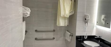 Un baño moderno con ducha, toallero, secamanos y lavamanos.