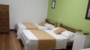 A hotel room with two beds, a wooden dresser, and a green wall. - Hotel Cañaveral Plaza (Manizales)