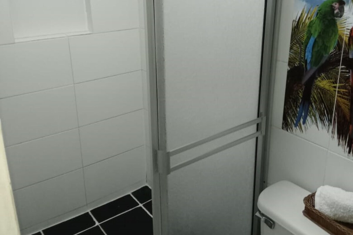 A bathroom with a shower, toilet, and a wall-mounted painting of a parrot.
