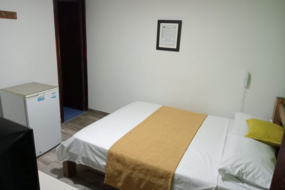 Una habitación con cama, escritorio, teléfono y puerta.