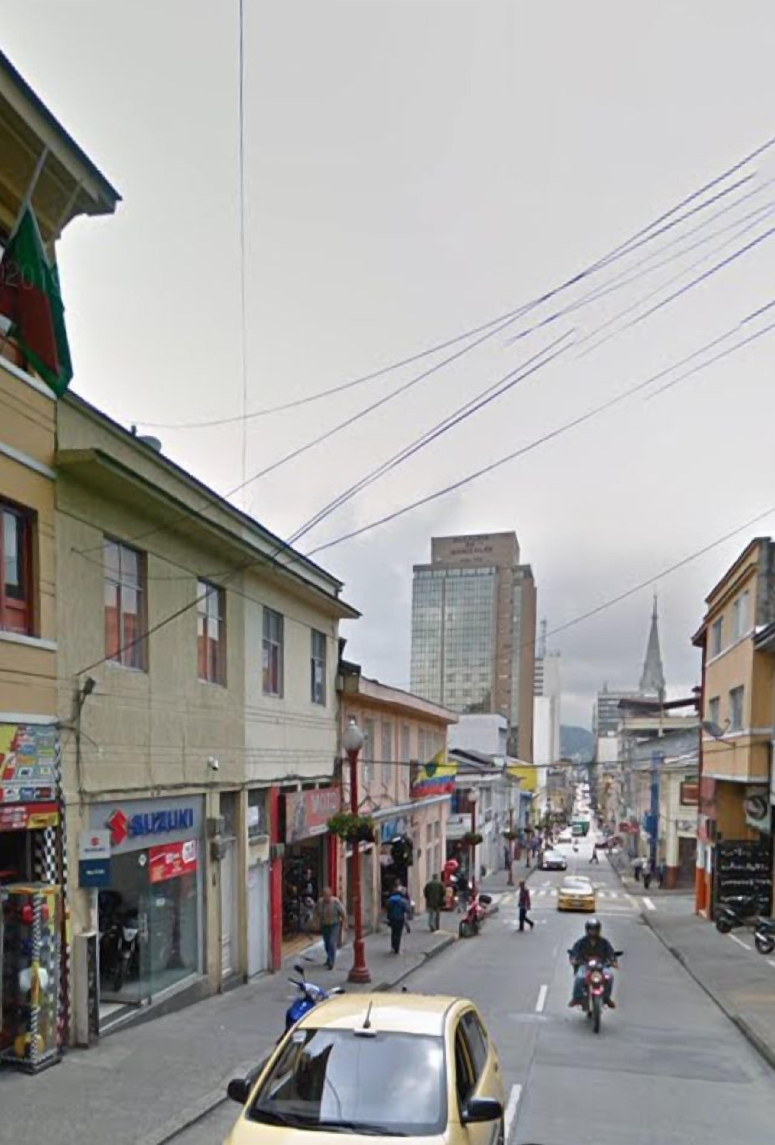 A street scene with a yellow car parked on the side, storefronts, and a building in the background.