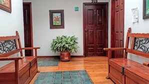 A hallway with wooden benches, a potted plant, and a door. - Hotel Cañaveral Plaza (Manizales)