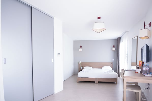Quarto de hotel moderno com uma cama grande, uma escrivaninha e uma televisão.
