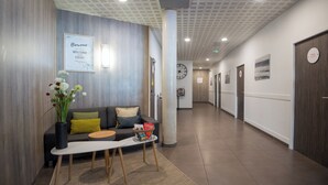A modern reception area with a sofa, a coffee table, and a vase of flowers.