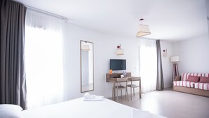 A hotel room with a large bed, a desk with a TV, and a sofa. - Zenitude Hotel-residences Narbonne (Narbonne)