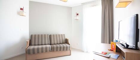 A modern living room with a sofa, a desk with a computer, a TV, and two wall-mounted lamps.