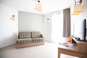 Una sala de estar moderna con un sofá, un escritorio con una computadora, un televisor y dos lámparas de pared.