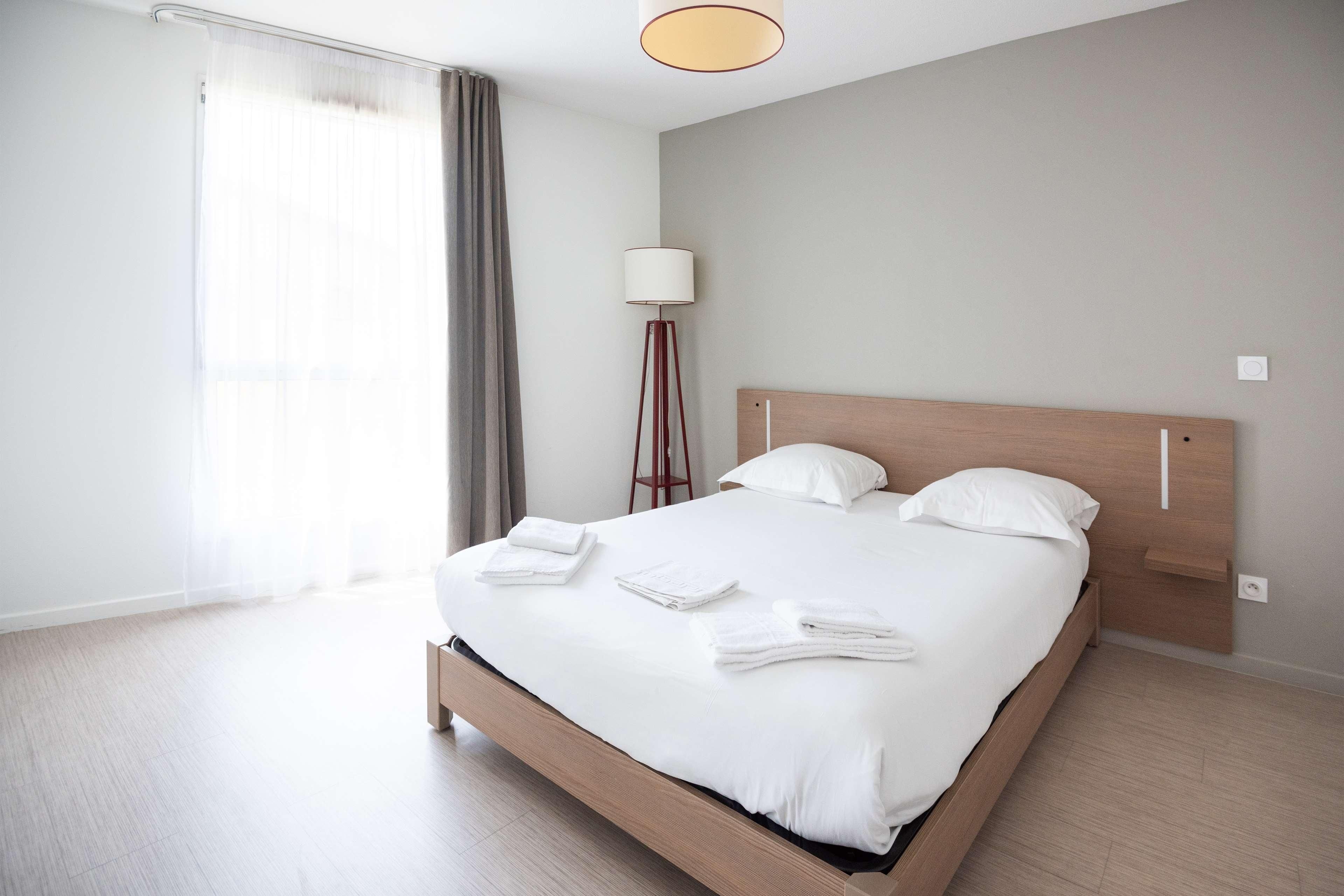 Une chambre d’hôtel moderne avec un grand lit, une lampe de chevet et une vue sur l’extérieur.