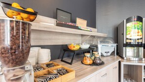 A breakfast bar with coffee, fruits, and condiments.