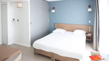 Habitación de hotel con cama, mesita de noche, lámpara y vistas al exterior.
