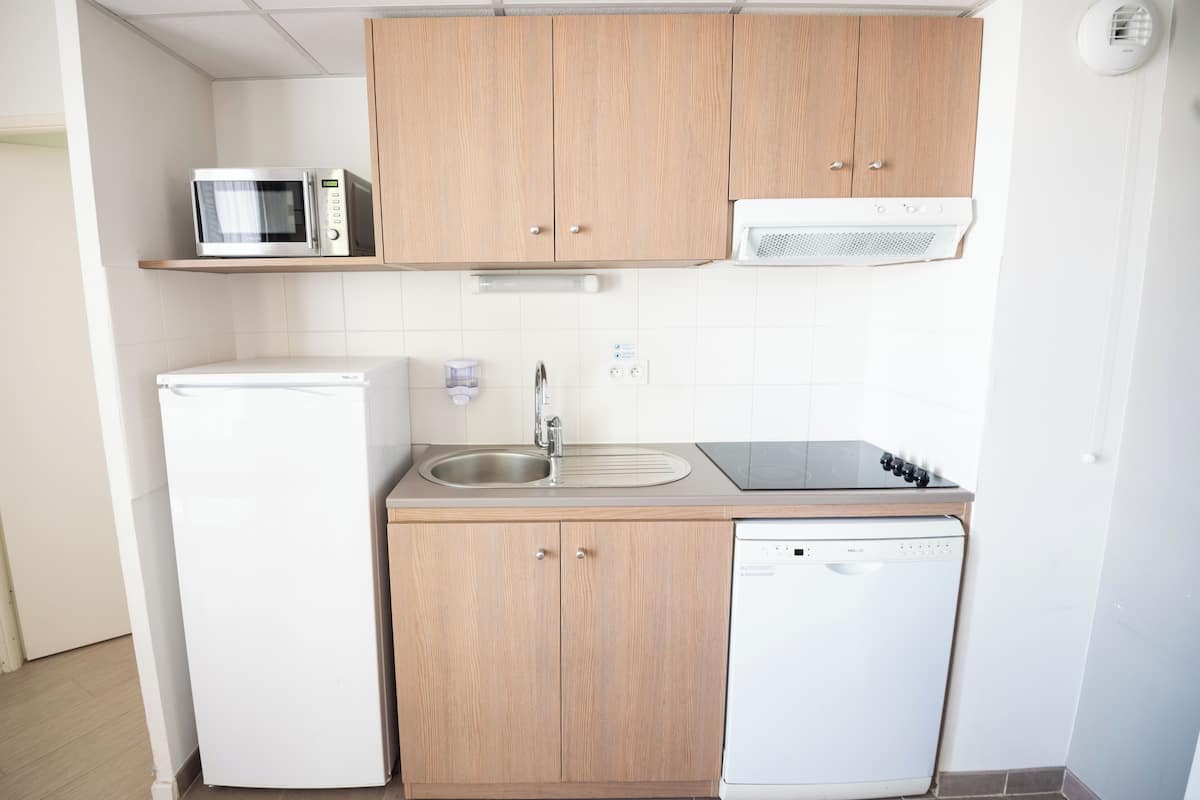A compact kitchen with a microwave, refrigerator, sink, stove, and dishwasher.