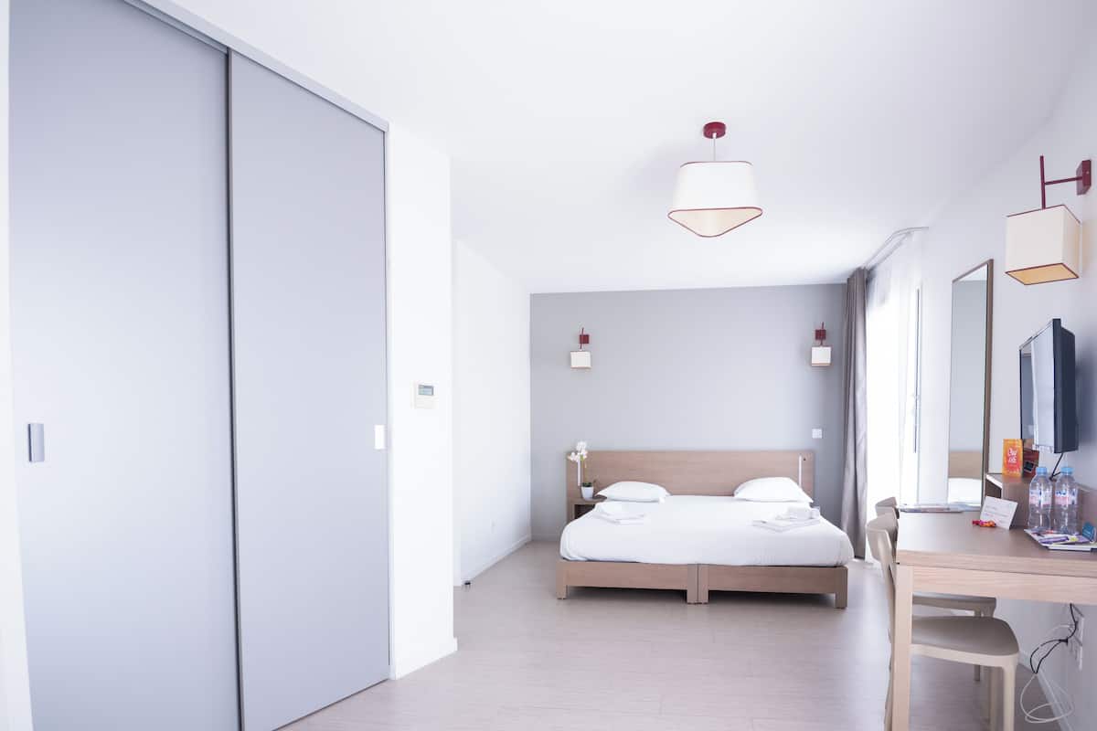 A modern hotel room with a large bed, a desk, and a TV.