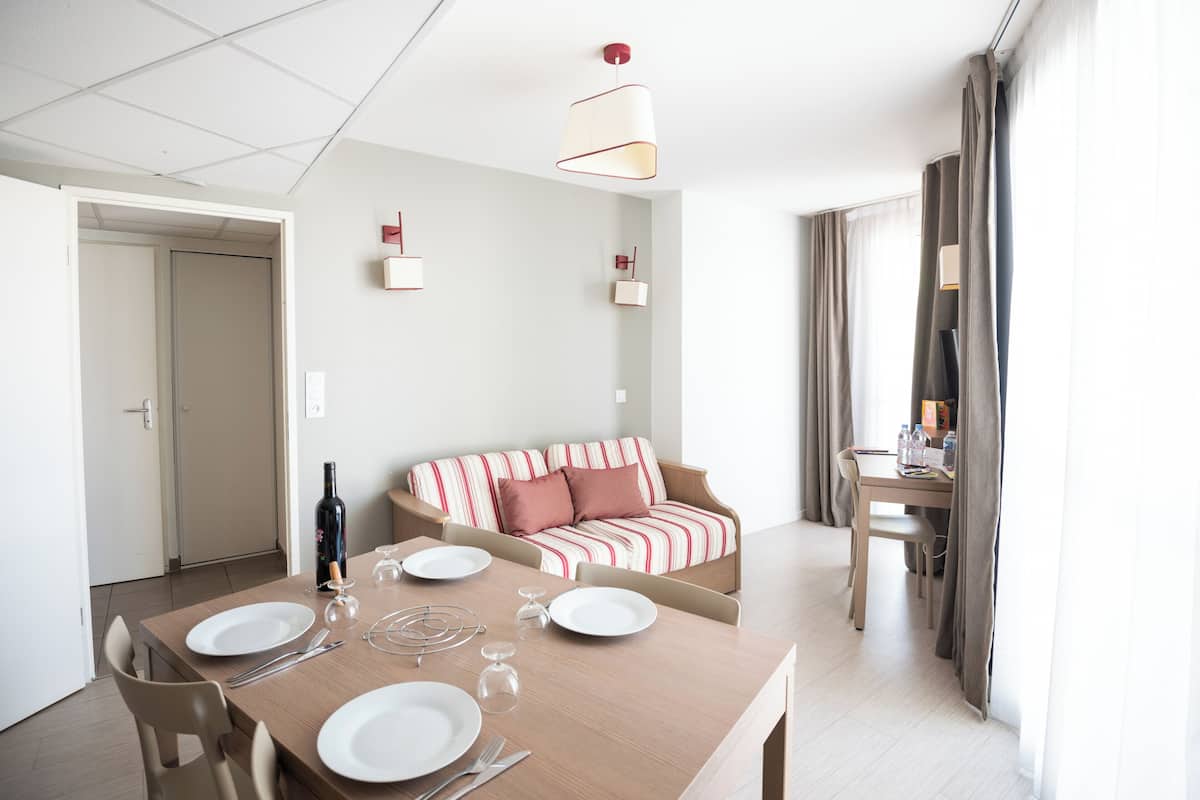 A dining area with a table set for four, a sofa, and a TV in the background.