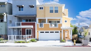 A multi-story residential building with a garage, a balcony, and a small porch area.