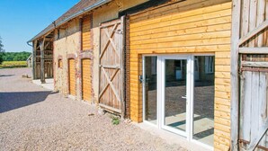 A barn with wooden doors and a gravel driveway.