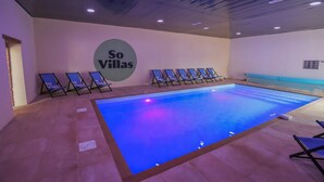 A swimming pool area with lounge chairs and a sign reading "So Villas".