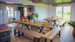 Un comedor moderno con mesas y bancos de madera, una planta central y vistas al exterior.