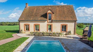 Una casa con piscina, zona de estar exterior y jardín.