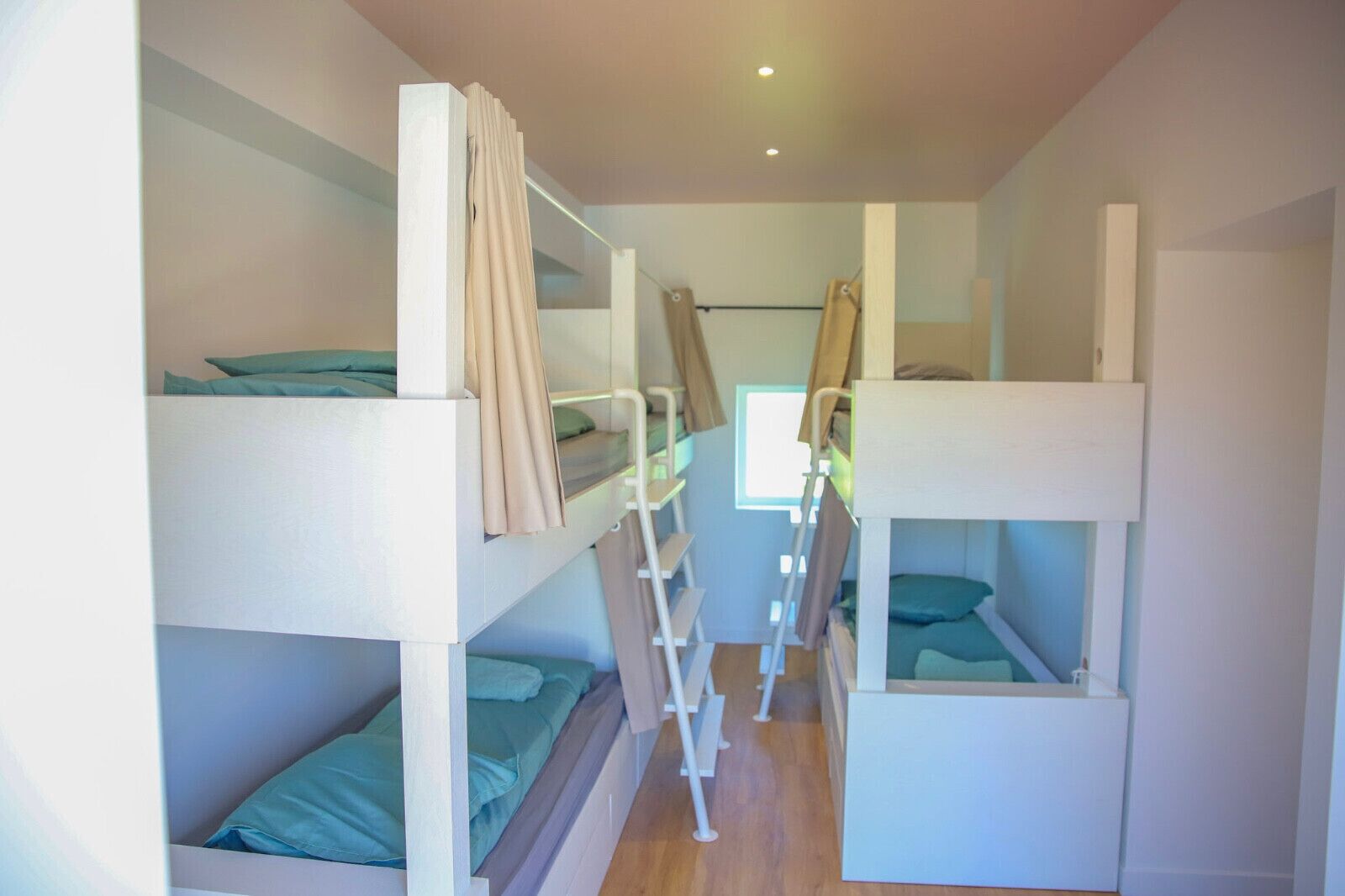 Habitación con literas dobles, cada una con escalera, y una ventana que proporciona luz natural.
