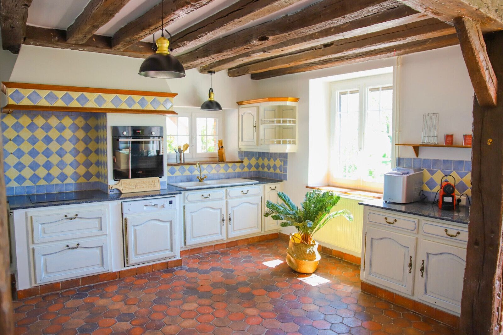 Une cuisine avec des meubles blancs, un pare-feu en carreaux et un sol à motifs hexagonaux.